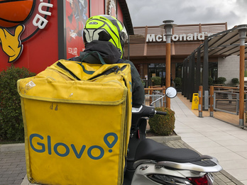 Un repartidor de Glovo a punto de montarse en su moto. (Raul BOGAJO / FOKU)